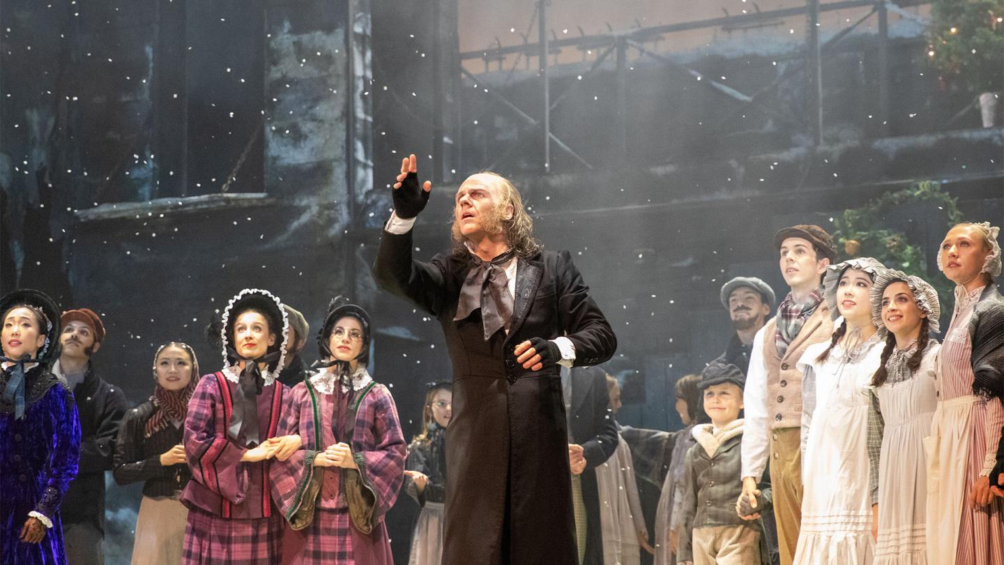A dancer stood in snow on stage looking out to the audience