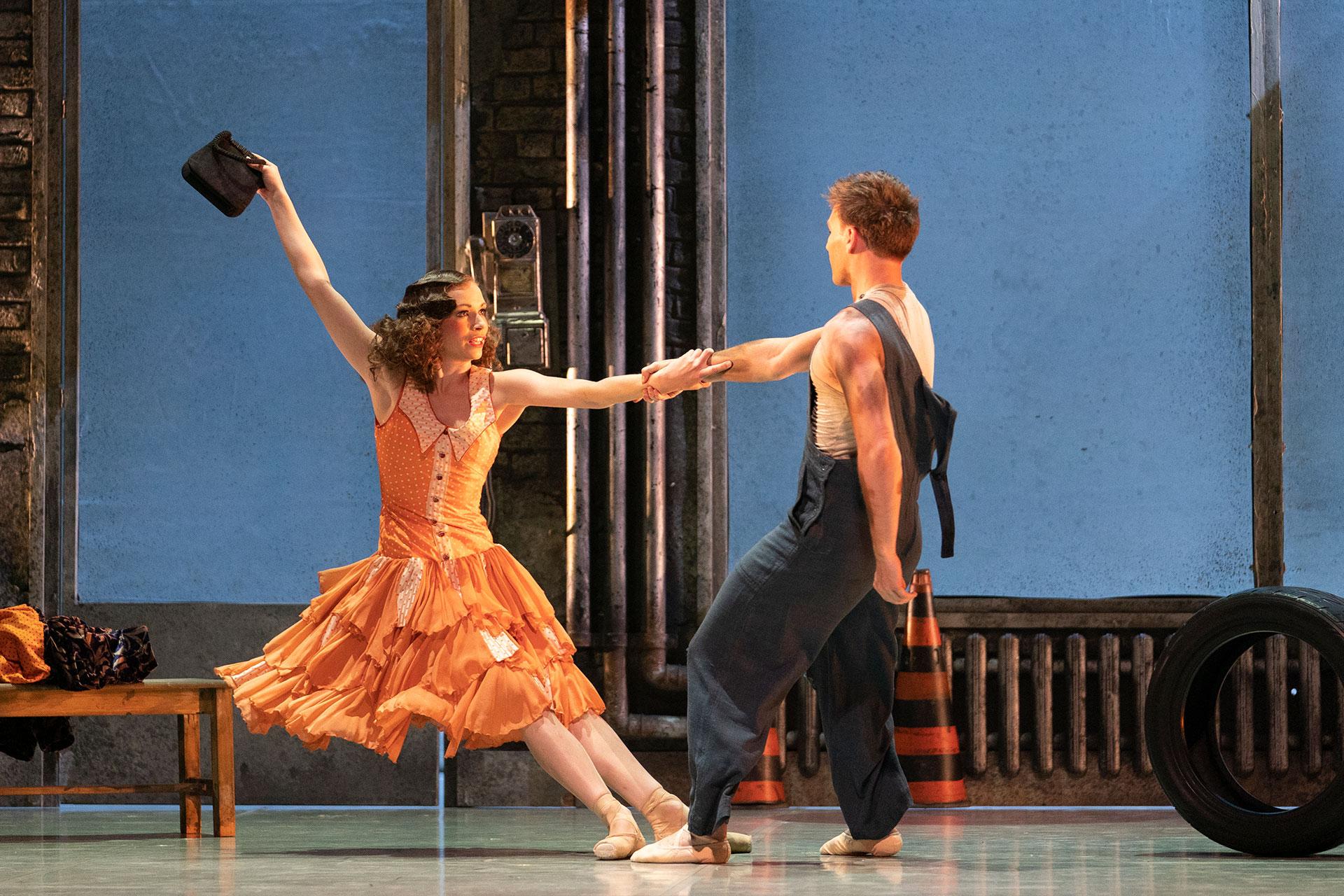 Abigail Prudames as Myrtle, wearing a bright orange dress, dances with her character's husband - the mechanic George played by Matthew Topliss. Photo Emma Kauldhar