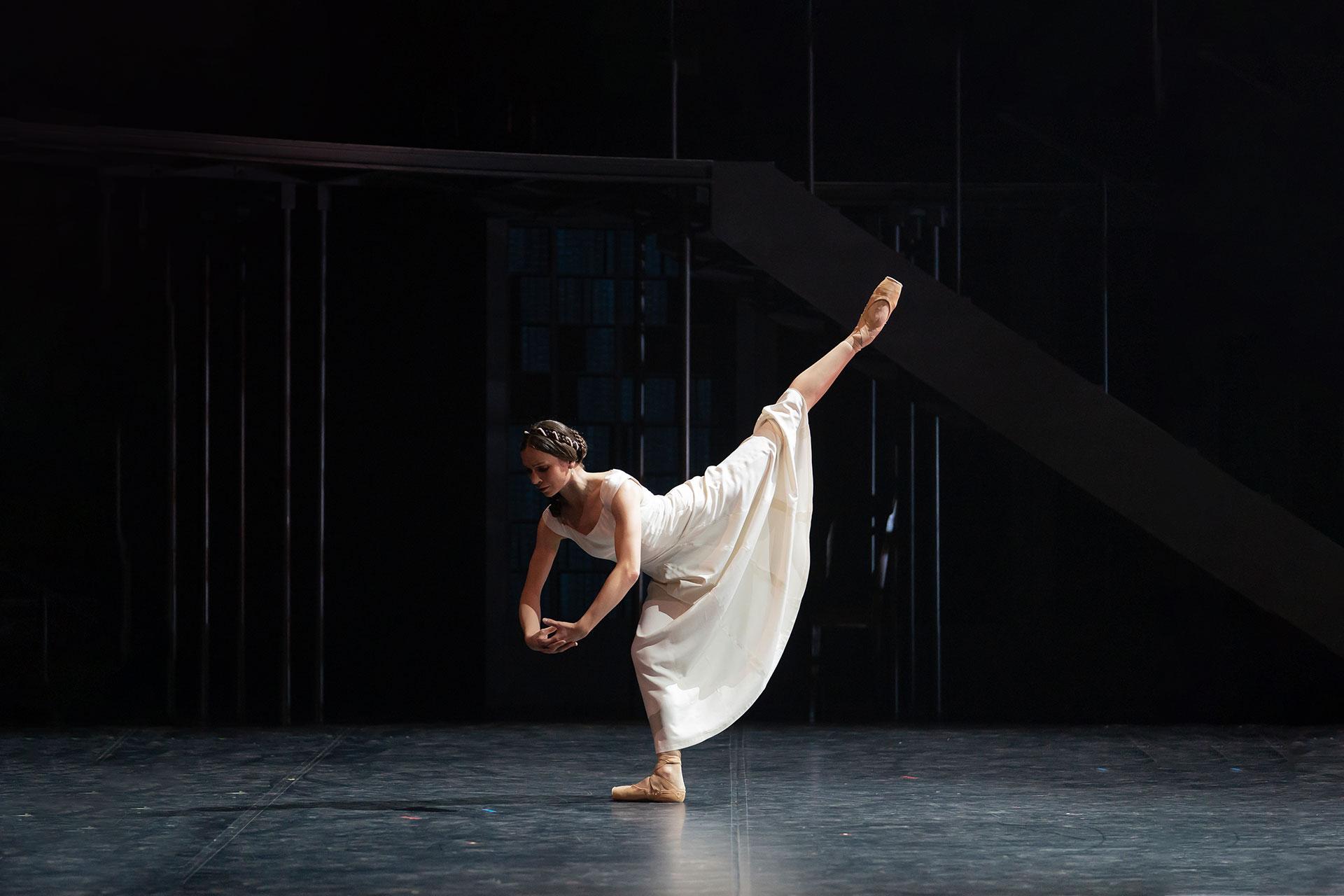 Victoria leans forward and raise a leg high behind her