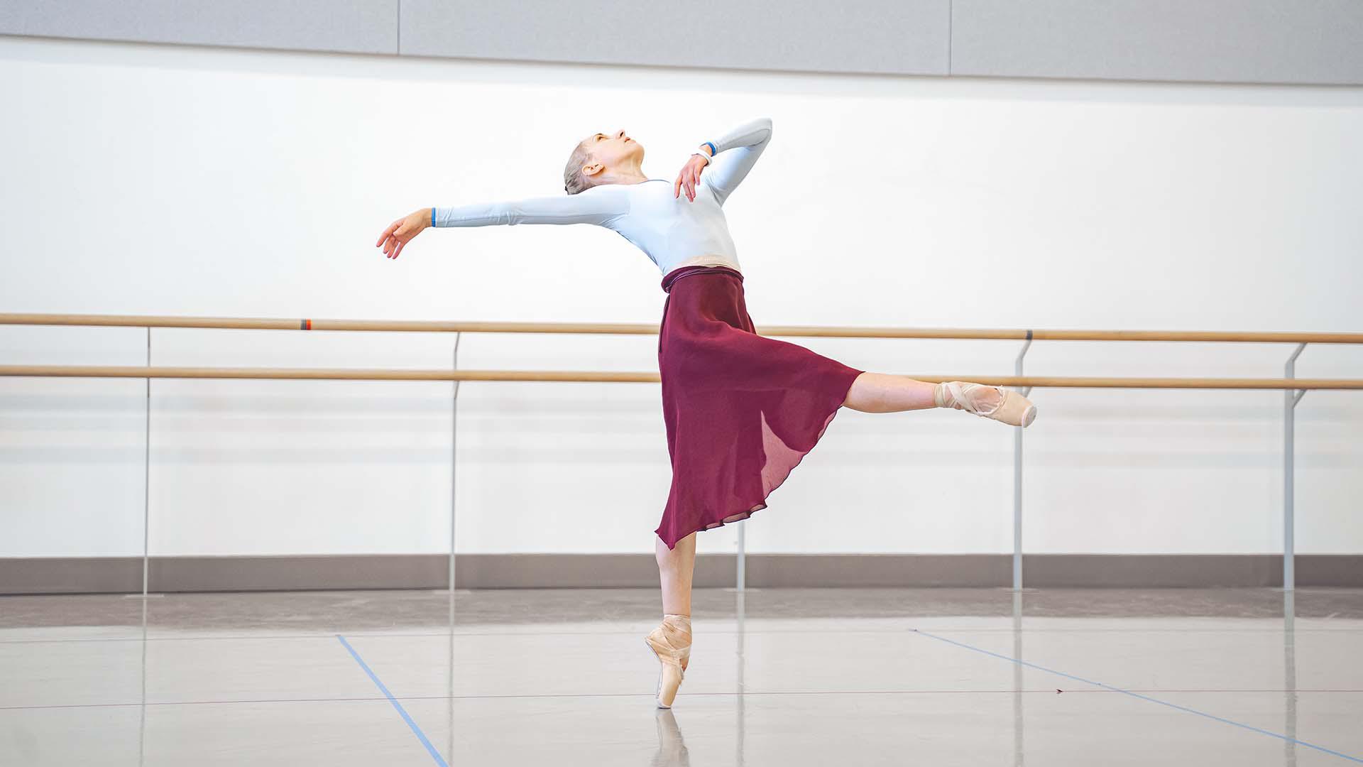 A female dancer standing on one leg with the other outstretched while her torso is leaning back.