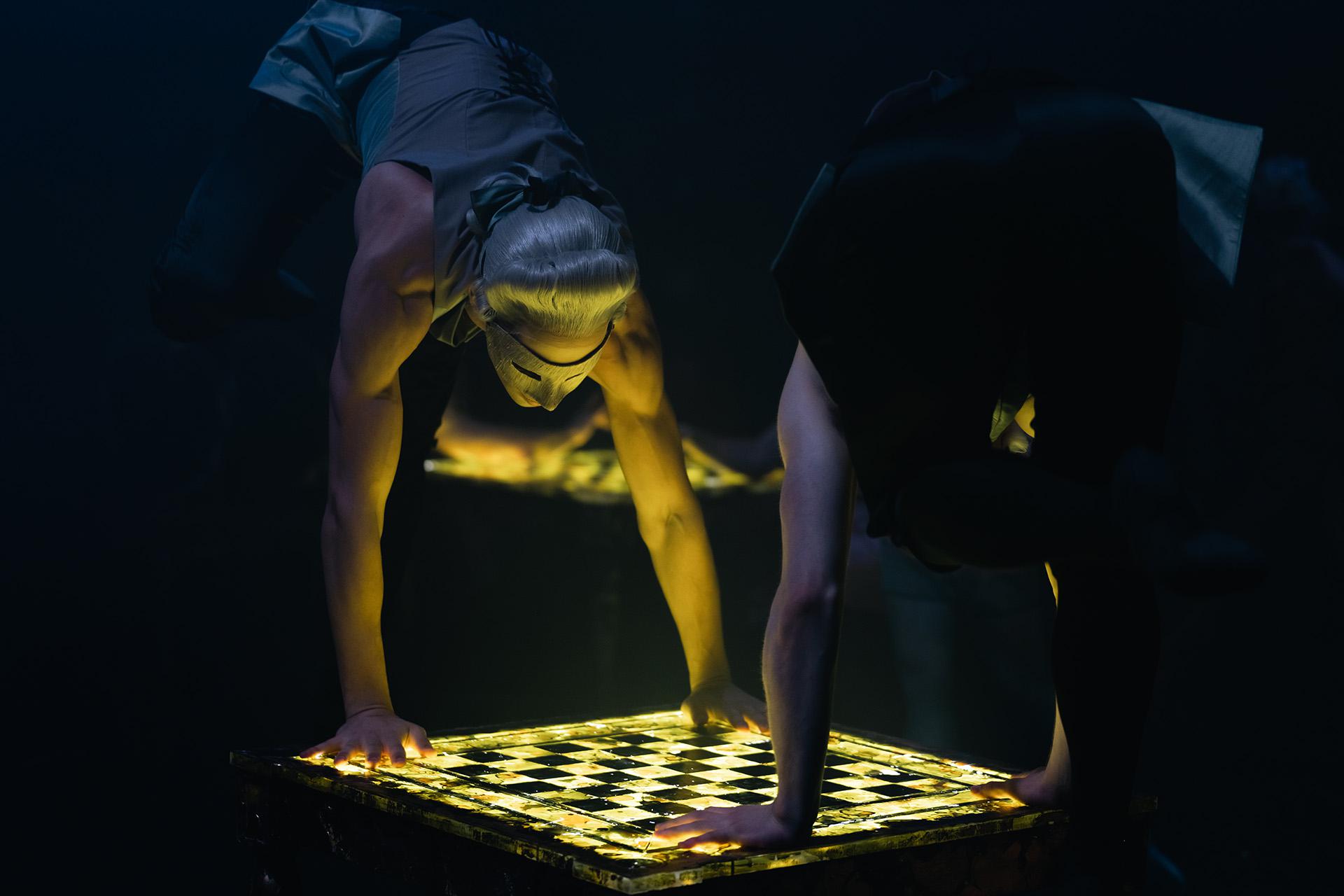 Dancers in masks illuminated by gaming tables they are leaning against