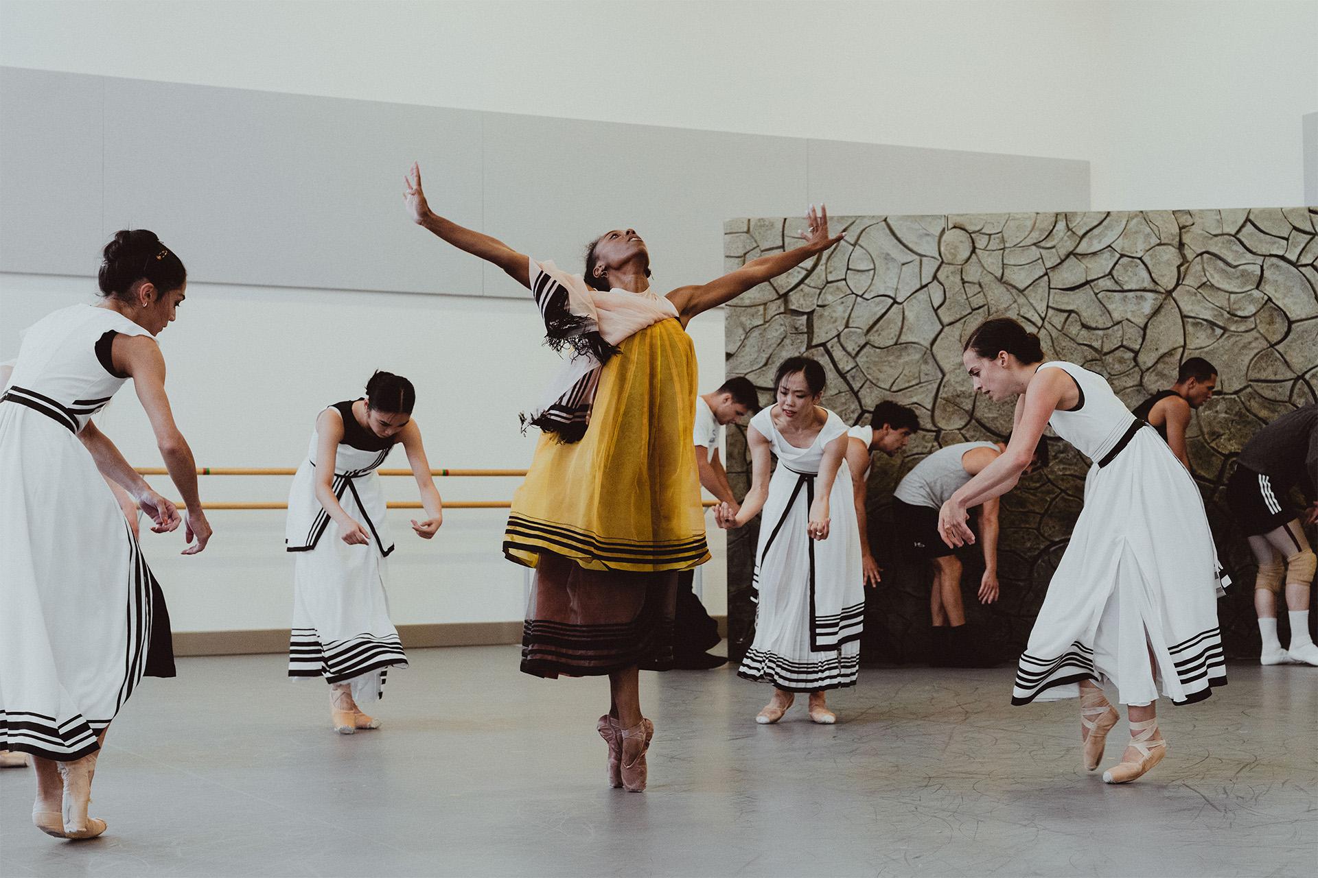Four dancers are around a fifth standing, arms outstretched, en pointe, and head back