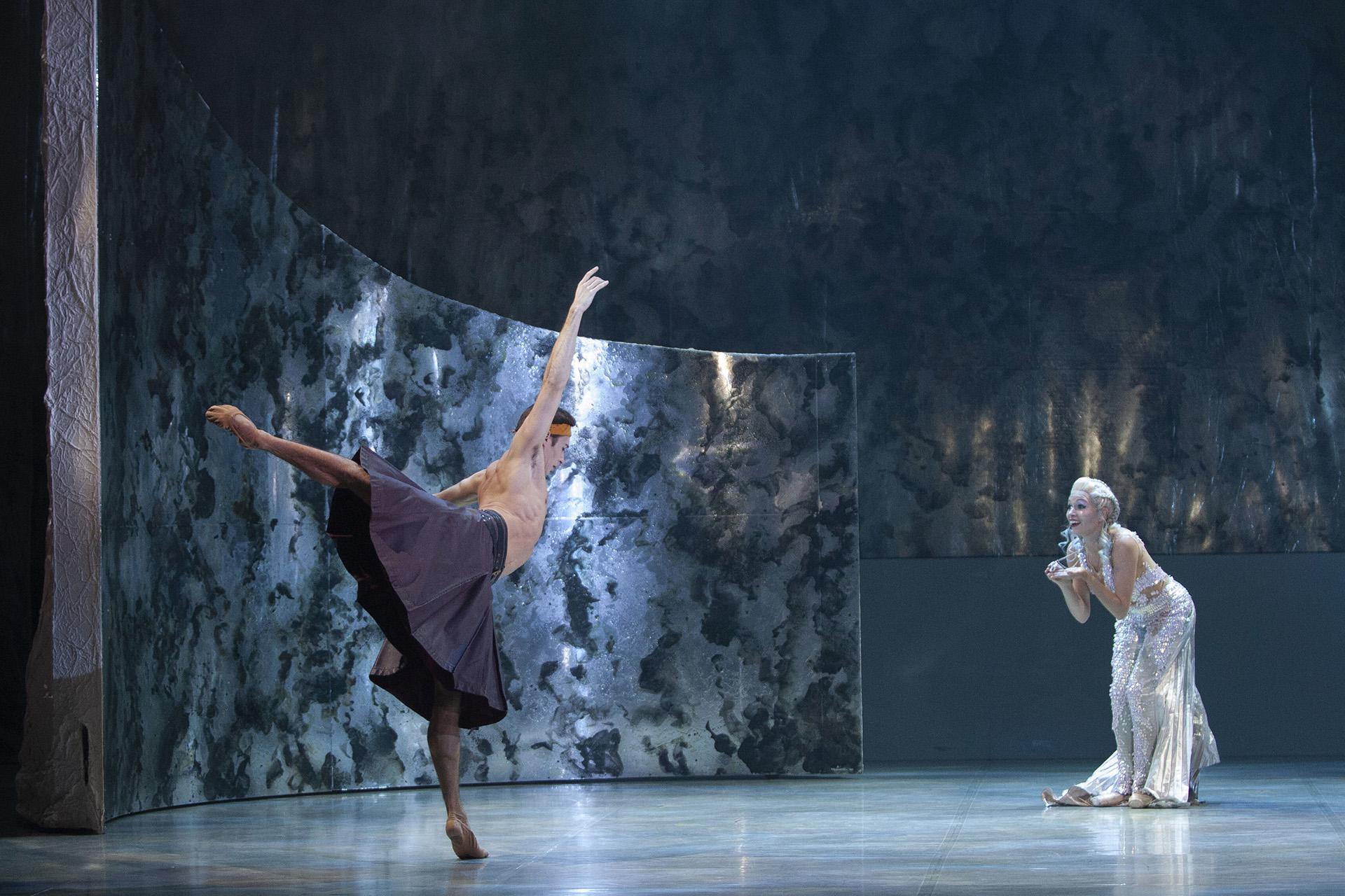 Prince Adair, wearing only a kilt, dances in front of Marilla, the little mermaid