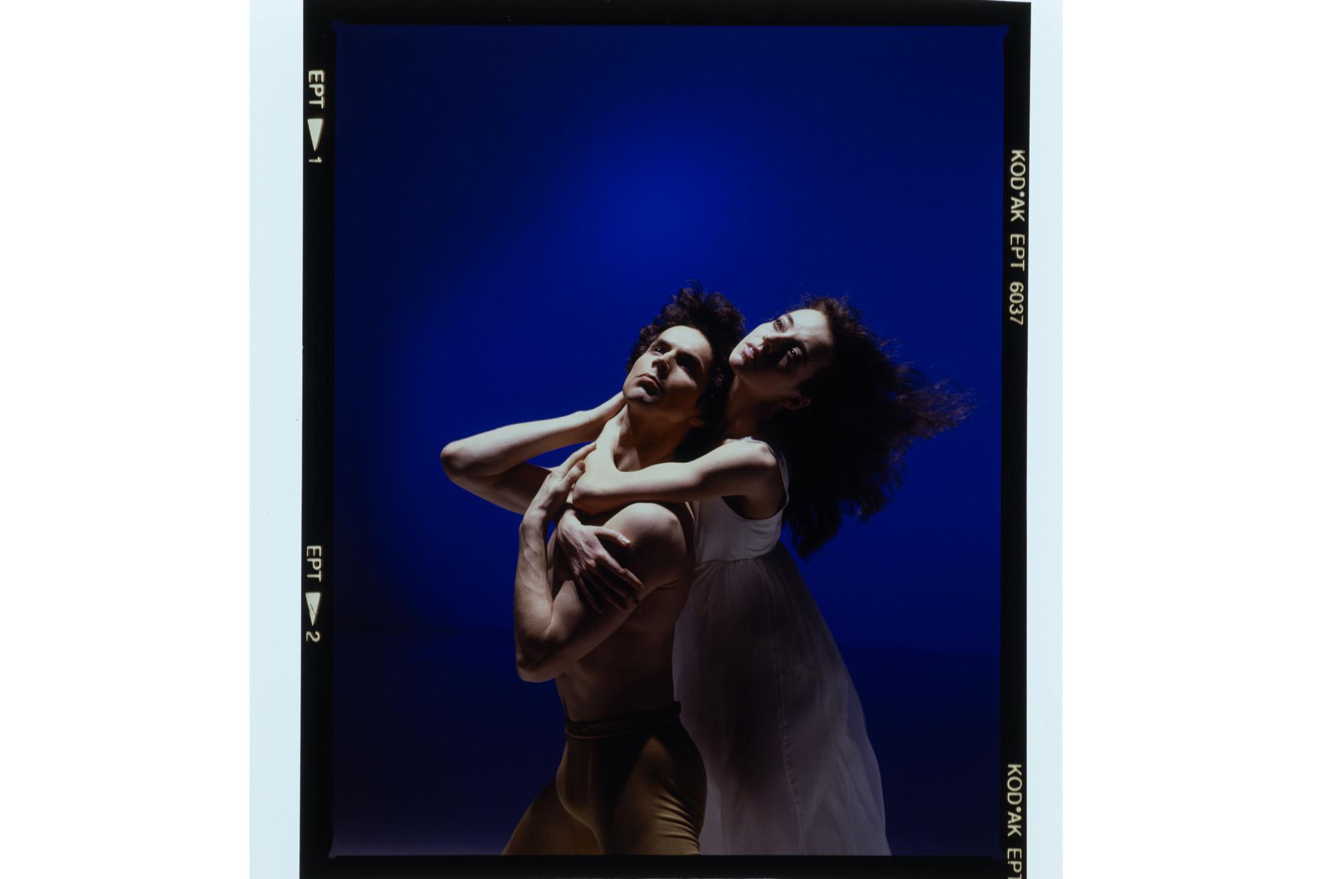 Two dancers stood embracing in a classical pose