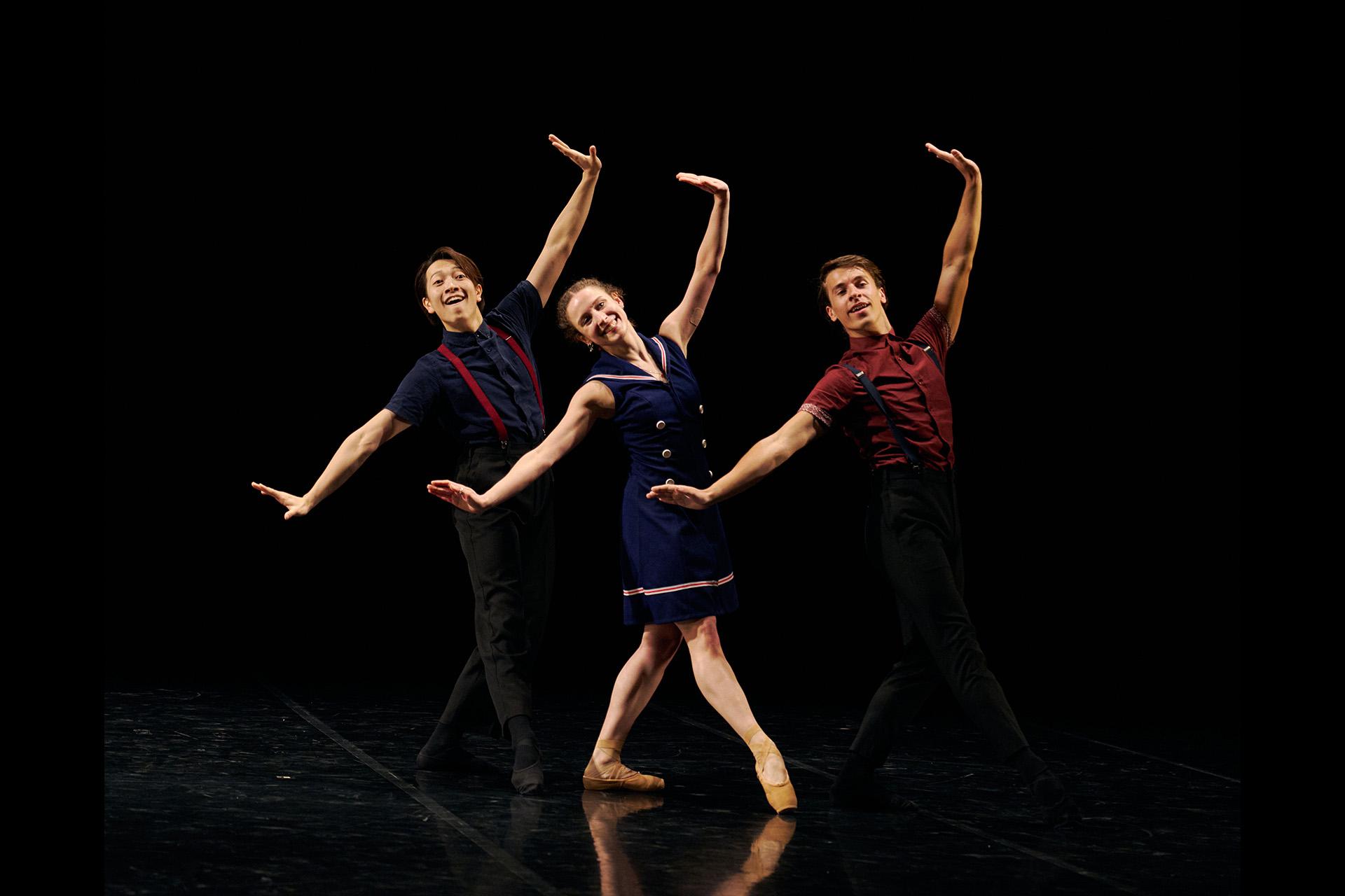 Three dancers smiling stood in a ros, smiling with arms wide
