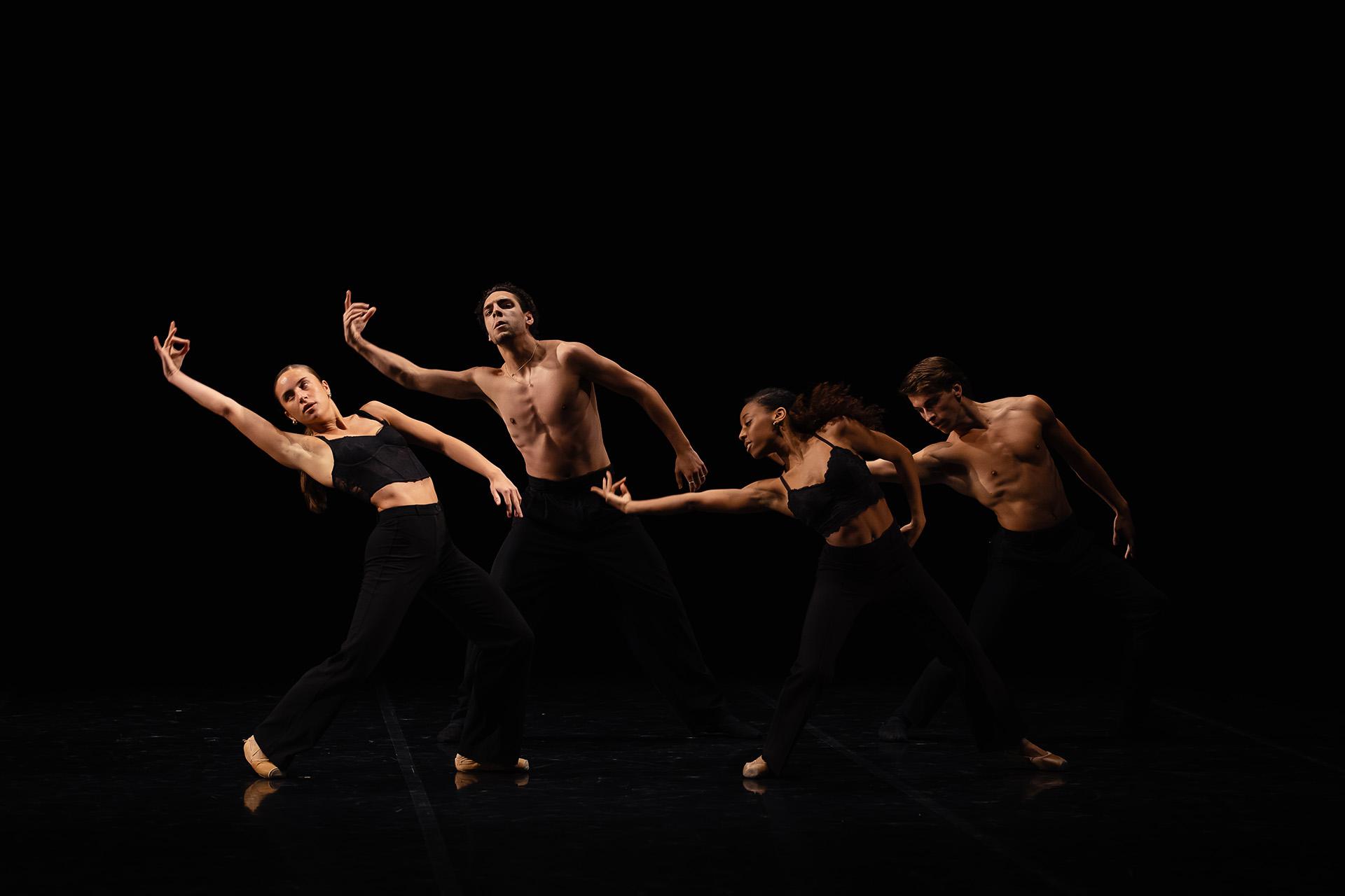 Four dancer in black pose leaning with an arm stretched