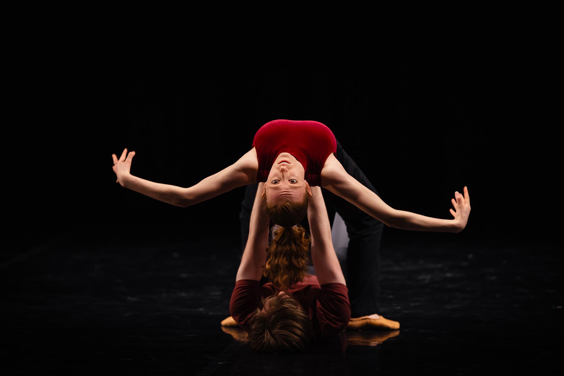 Dancer in is lifted horizontally on her back by another dancer laying flat on the floor