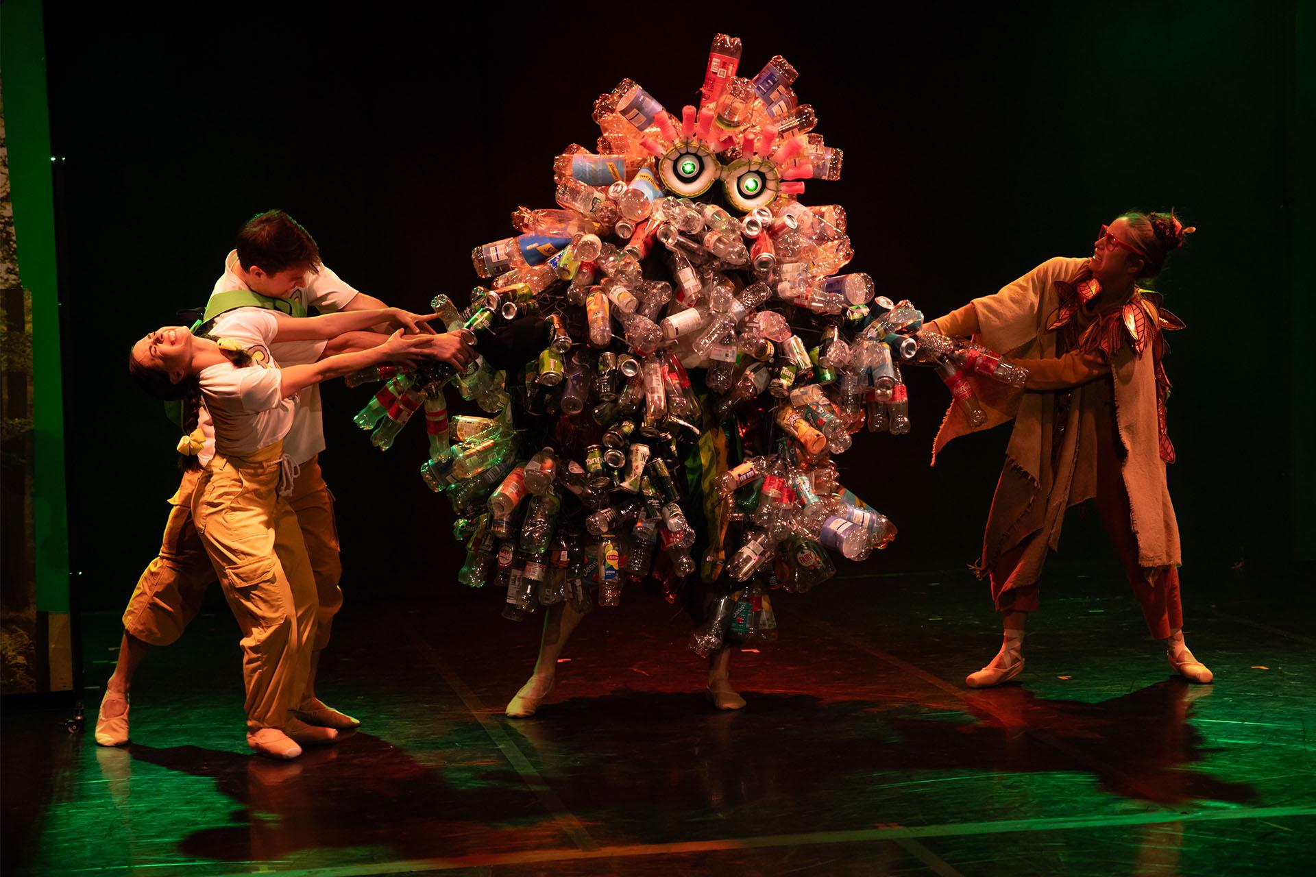 Hansel, Gretel and the Lady of the Forest pull the plastic bottles and cans off the Rubbish Monster.