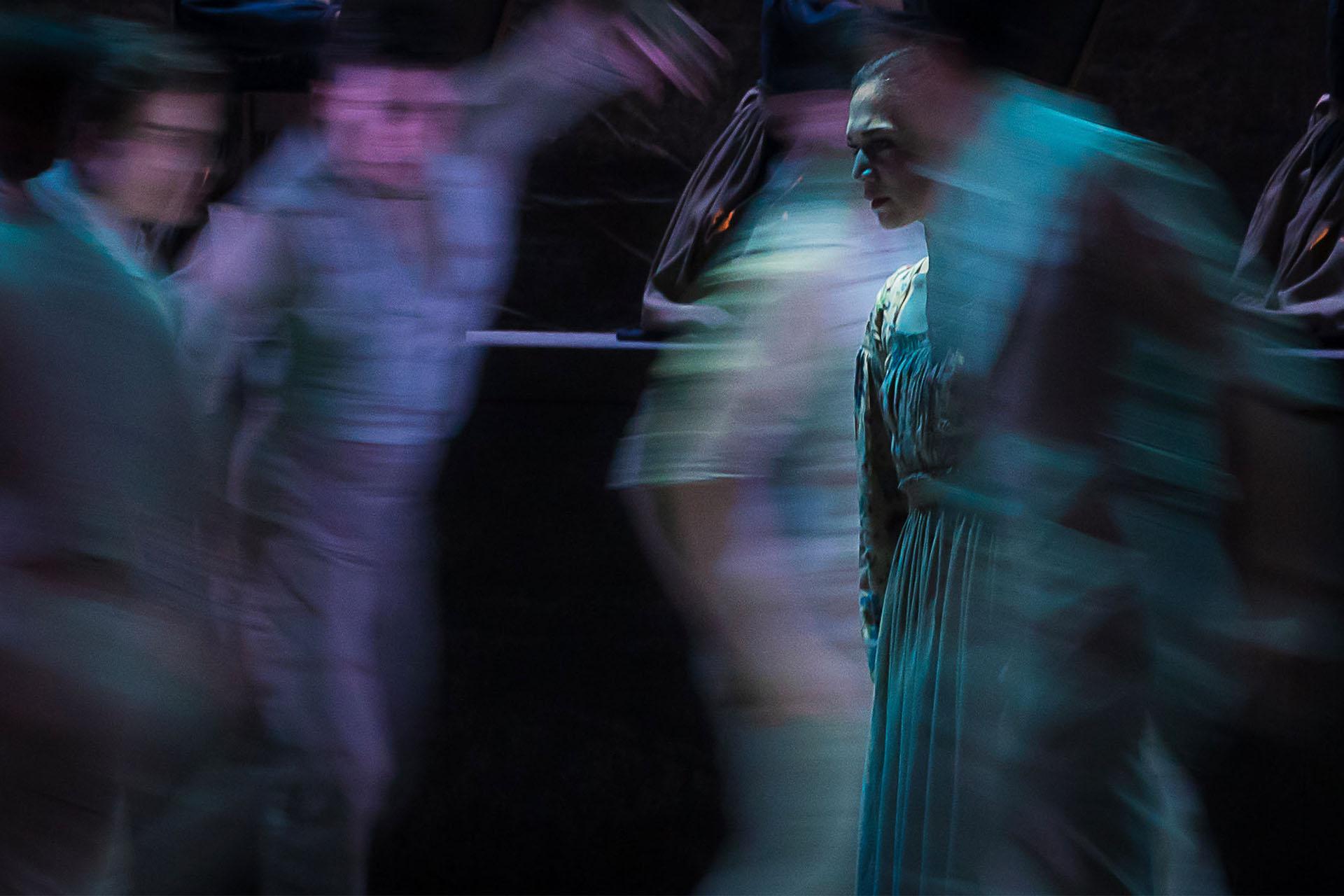 Jane Eyre is in focus while around her, blurred by quick motion, are people dancing incoherently around her