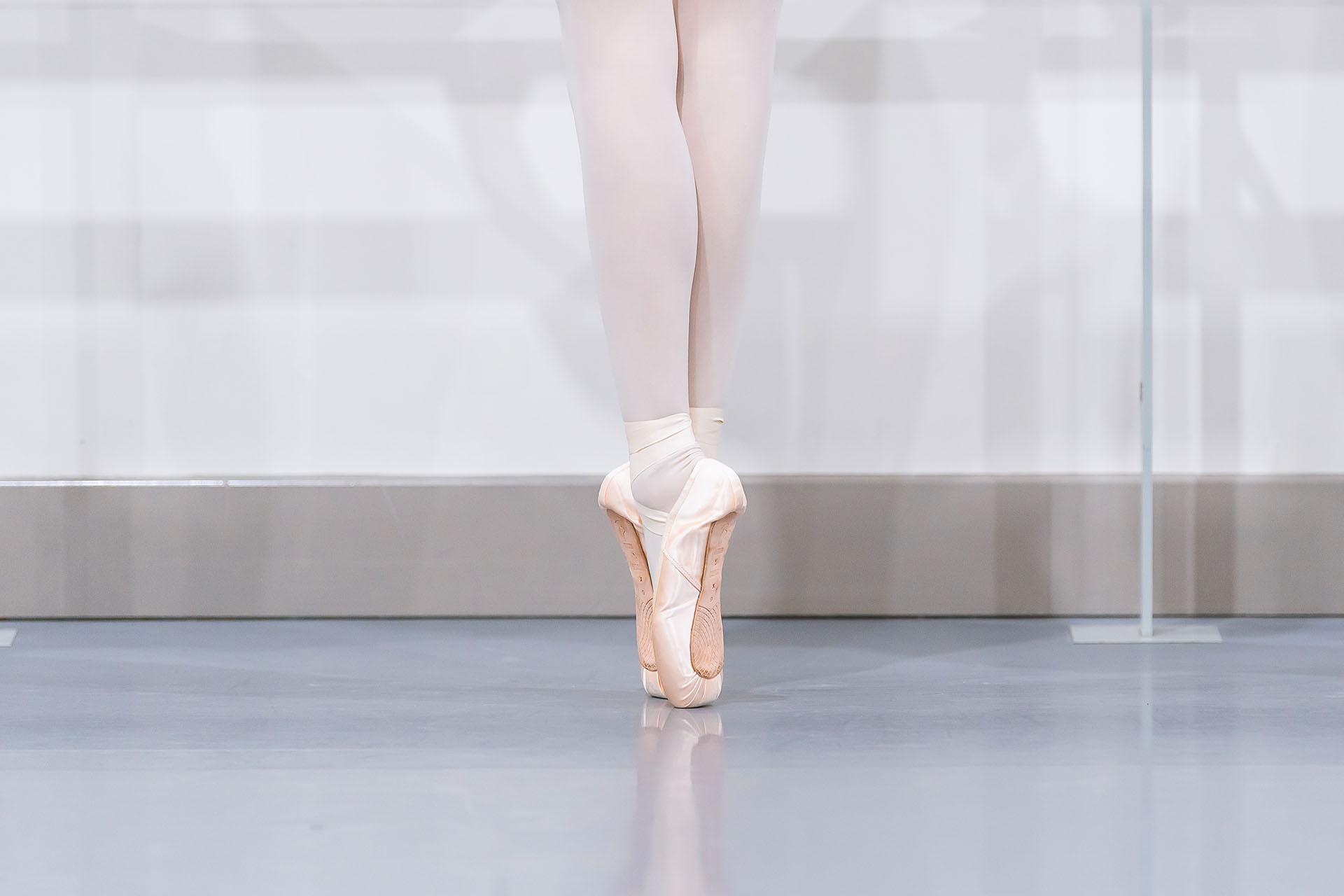 Close up on pointe shoes word and the toes against the grey studio floor