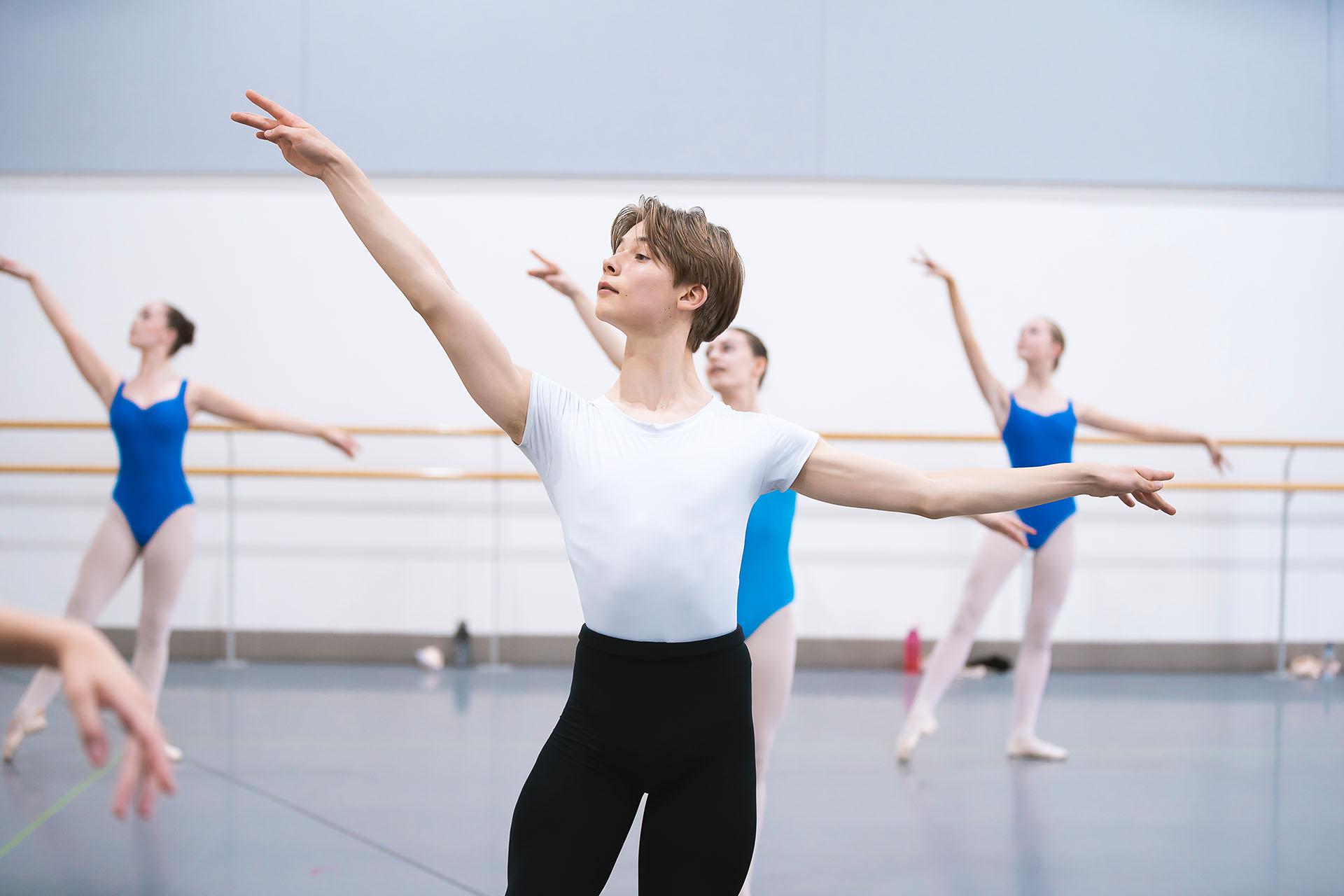 Male Centre for Advanced Training student in a white top and black trousers posing with his left arm our horizontally and his right raised slightly