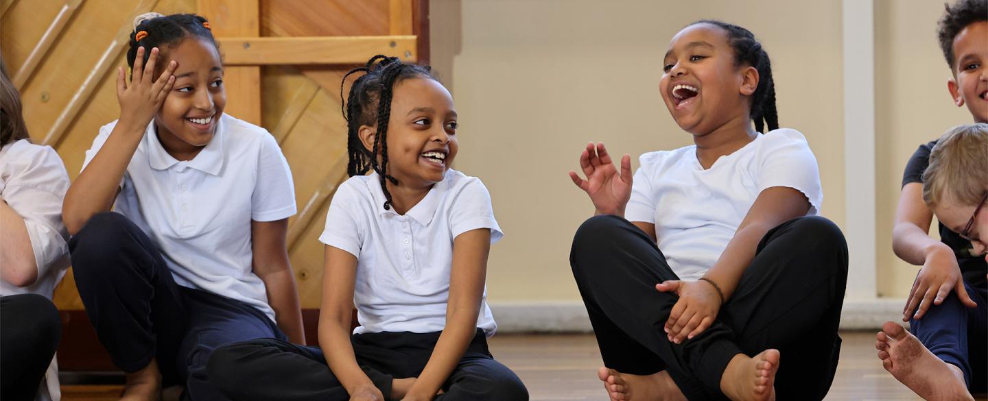 Three girls sat on the floor cross-legged, laughing