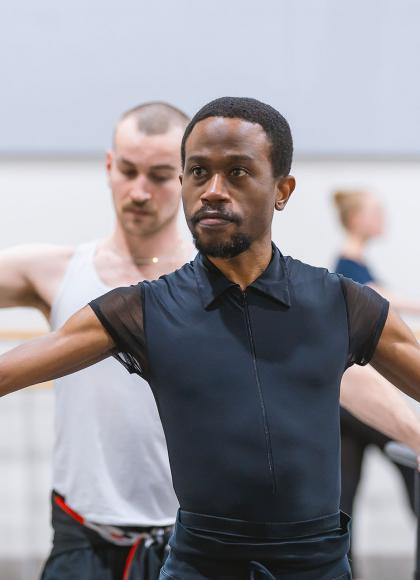 Male student dancer at the barre, holding a pose, his look intense