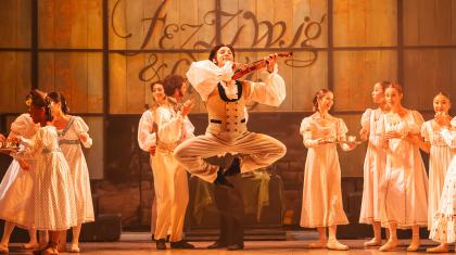 Dancer in Victorian dress, leaping high with a fiddle under his chin