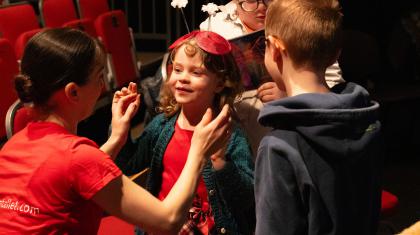 A child is wearing part of the costume for a Children's Ballet to feel closer to the action