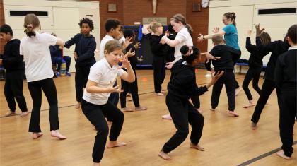 School children in a PE hall practice moves and dancing in a safe place