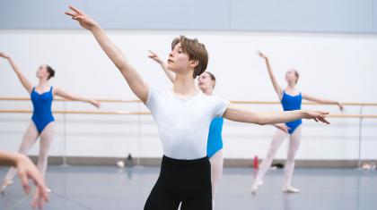 Male Centre for Advanced Training student in a white top and black trousers posing with his left arm our horizontally and his right raised slightly
